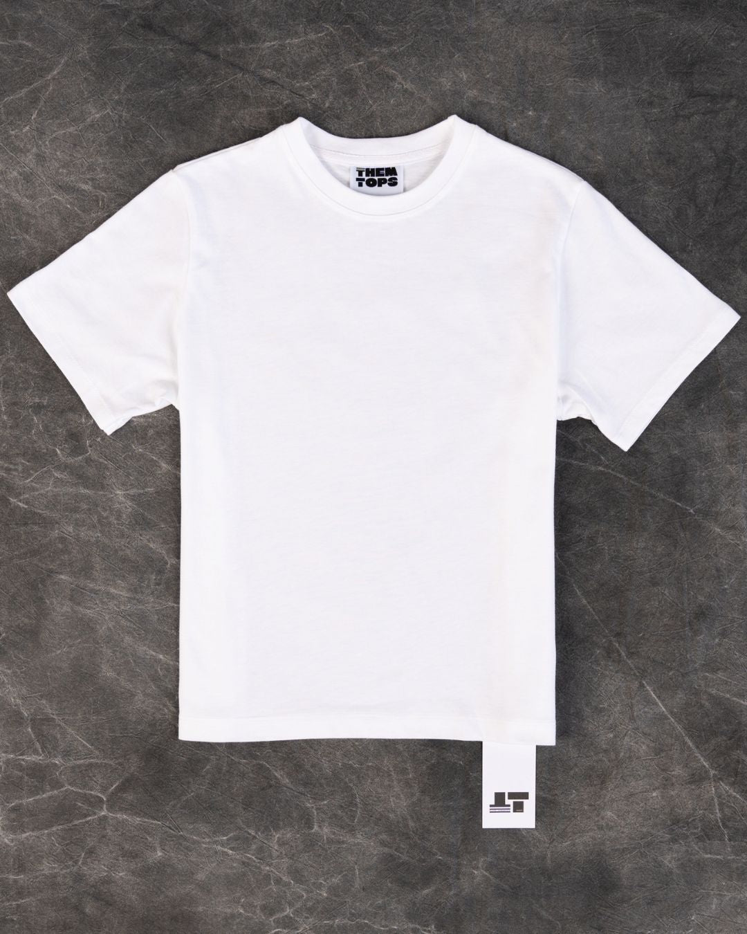 A plain white short-sleeve crewneck t-shirt laid flat on a dark gray textured background. 